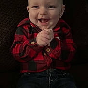 John joined the competition — help win amazing prizes! baby, child, smiling, happy, red_shirt, checkered_shirt, jeans, clothing, hands, face, sitting, portrait, indoor, cute, infant, young_child, person, casual, joyful, background