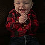 baby, child, smiling, happy, red_shirt, checkered_shirt, jeans, clothing, hands, face, sitting, portrait, indoor, cute, infant, young_child, person, casual, joyful, background
