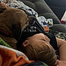 child, dog, couch, blanket, relaxing, indoor, resting, comfort, sleeping, pet, home, cozy, casual, toddler, furniture, blanket_pattern, soft_light, window_blinds, paw, clothing