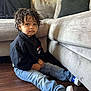 Dior is registered to the contest to win money with this photo: black_jacket, casual_clothing, child, couch, curly_hair, cute, expression, floor, furniture, home_interior, indoor, jeans, living_room, person, portrait, relaxed, sitting, sneakers, wooden_floor, young_child