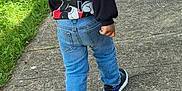 Dior is registered to the contest to win money with this photo: back_view, casual_clothing, child, curly_hair, cute, daylight, fashion, grass, jeans, kid, mickey_mouse, outdoor, pavement, person, sidewalk, sneakers, sweatshirt, urban, walking, young