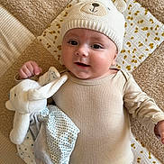 Maël participe au concours pour gagner de l'argent avec cette photo : baby, infant, child, knit_hat, bear_ears, plush_toy, blanket, beige_clothing, lying_down, soft_texture, cute, smiling, indoors, closeup, cozy, comfort, happy, person, headwear, playful