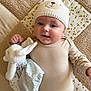 baby, infant, child, knit_hat, bear_ears, plush_toy, blanket, beige_clothing, lying_down, soft_texture, cute, smiling, indoors, closeup, cozy, comfort, happy, person, headwear, playful