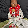 baby, bib, blanket, child, christmas, clothing, curly_hair, cute, face, holiday, indoor, infant, pajamas, patterned, quilt, red, reindeer, smile, socks, striped