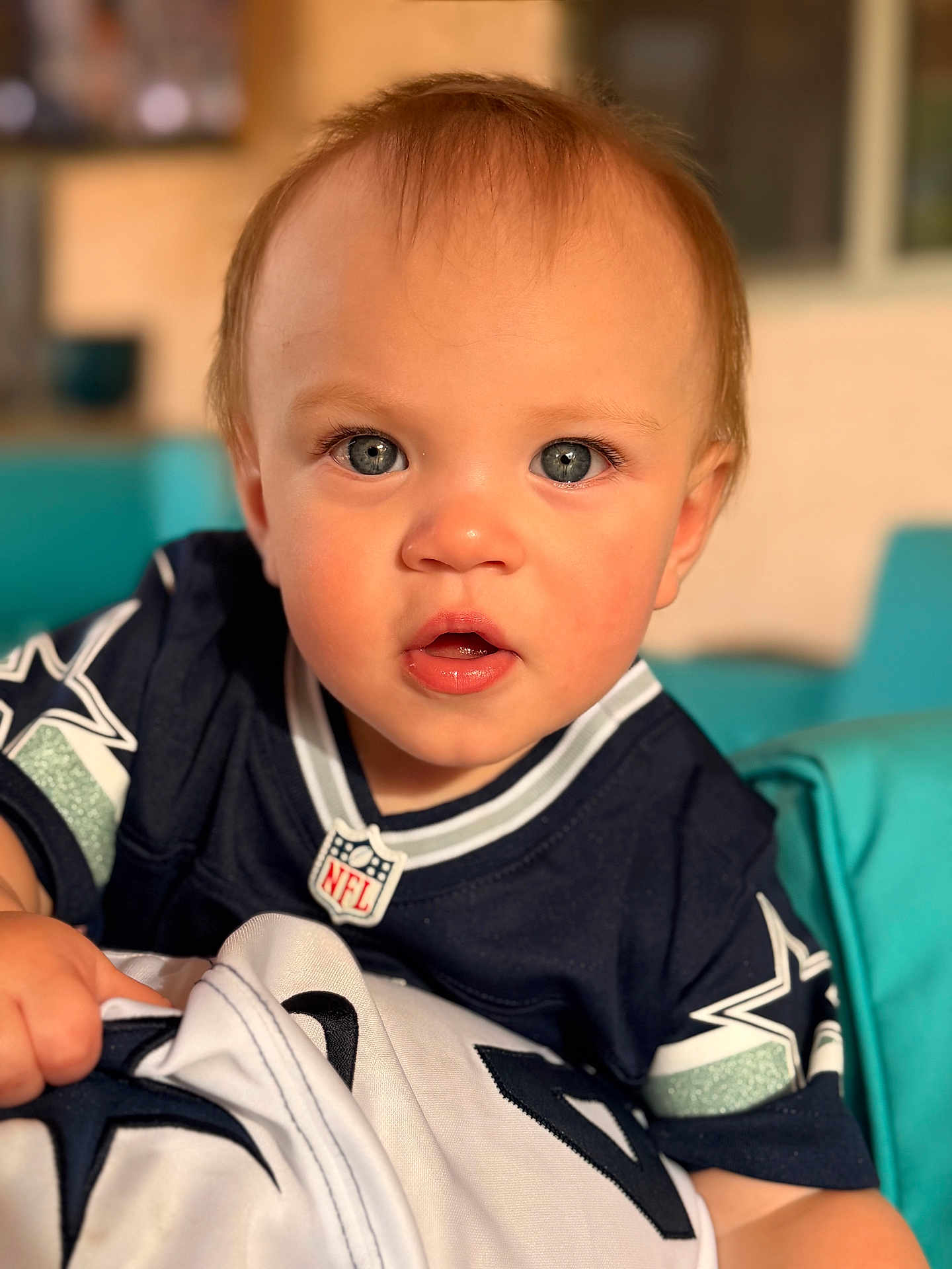 Walker Lee is registered to the contest to win money with this photo: baby, child, infant, face, blue_eyes, jersey, nfl, dallas_cowboys, sportswear, cute, portrait, indoors, soft_light, curious, grip, clothing, person, young_child, closeup, seated