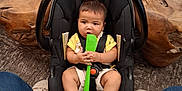 Onyx is registered to the contest to win money with this photo: baby, car_seat, child, indoor, person, wood, carpet, footwear, jeans, toy, holding, curious, sitting, black, green, spatula, decor, floor, slippers, cute