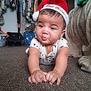 Onyx is registered to the contest to win money with this photo: baby, infant, santa_hat, carpet, indoor, clothing, face, child, cute, person, holiday, christmas, expression, hands, floor, home, furniture, closet, curious, pout