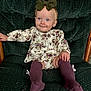 Braelynn is registered to the contest to win money with this photo: baby, bow, child, clothing, cushioned_chair, cute, fashion, floral_dress, green_chair, happy, headband, indoor, infant, person, portrait, purple_socks, seated, smiling, socks, wooden_armrest