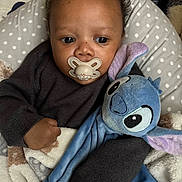 Keyron a rejoint le concours — aidez-le/la à gagner de superbes lots ! baby, child, pacifier, plush_toy, blanket, polka_dot, cushion, dark_sweater, indoor, close_up, face, hand, comfort, sleepy, cute, soft_toy, infant, resting, warm, portrait