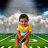 baby, child, football, sports, stadium, field, green_grass, yellow_shirt, smiling, cute, holding, sitting, sports_equipment, helmet_logo, clouds, lights, portrait, outdoor, young_child, person