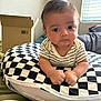 Blake joined the competition — help win amazing prizes! baby, infant, pillow, checkered_pattern, clothing, hands, face, eyes, indoors, window, cardboard_box, bed, blanket, toy, curious, closeup, child, person, soft_light, casual