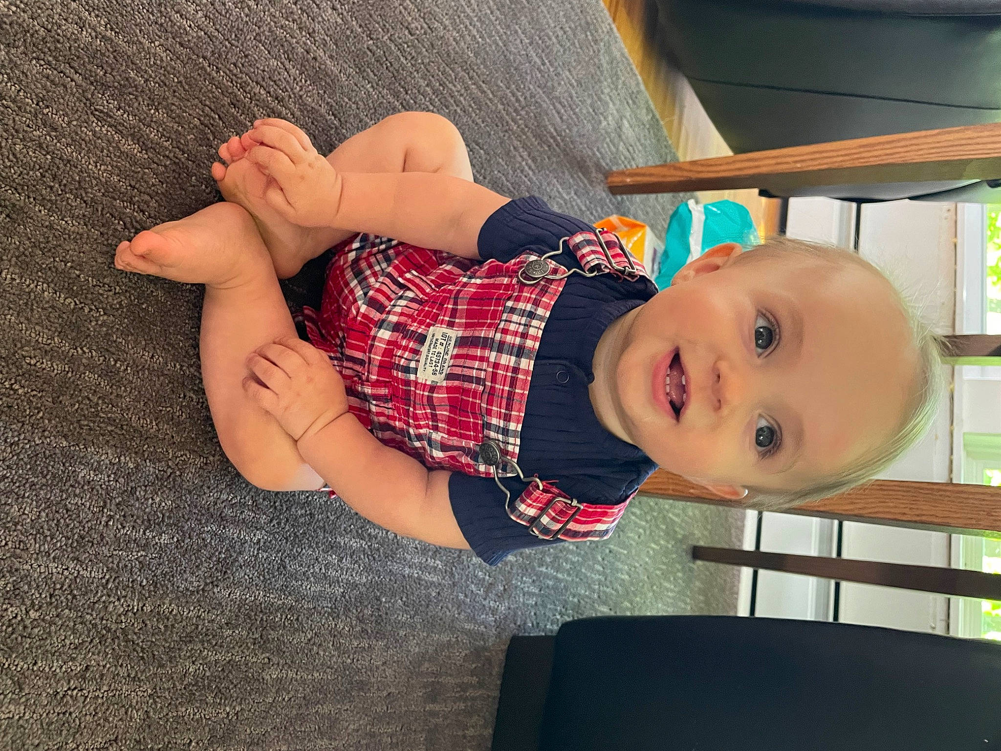 Maxton is registered to the contest to win money with this photo: baby, baby_toddler_clothing, comfort, eye, face, finger, glasses, hand, head, human_body, leg, mammal, person, plaid, shelf, skin, sleeve, smile, tartan, toddler