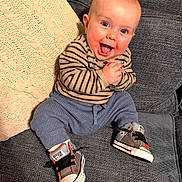 Max joined the competition — help win amazing prizes! baby, smiling, sitting, couch, striped_clothing, converse_shoes, happy, indoor, furniture, cozy, hands_clasped, blue_pants, knitted_pillow, cute, child, portrait, head, footwear, person, expression