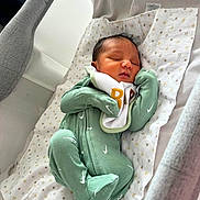 Junior is registered to the contest to win money with this photo: baby, newborn, sleeping, onesie, green_clothing, bassinet, blanket, stars_pattern, infant, cozy, peaceful, indoor, soft_light, cute, child, resting, baby_bedding, baby_clothes, head, person