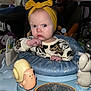 Everleigh is registered to the contest to win money with this photo: baby, infant, child, headband, yellow_bow, skeptical_expression, blue_eyes, onesie, leopard_print, activity_center, toy_snail, plastic_toy, tray, indoor, living_room, recliner, adult_in_background, hand_on_chin, flash_lighting, portrait