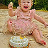 Everleigh is registered to the contest to win money with this photo: barefoot, birthday, cake, celebration, child, face_paint, frosting, fun, greenery, happy, headband, messy, nature, outdoor, pink_dress, playful, sand, smiling, sprinkles, toddler