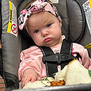 Everleigh is registered to the contest to win money with this photo: baby, infant, child, car_seat, headband, pink_clothing, blanket, harness, buckle, face, blue_eyes, grumpy_expression, hand, shopping_cart, warning_label, fabric, seat_padding, portrait, indoor, cute