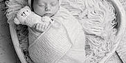 Edgar participe au concours pour gagner de l'argent avec cette photo : newborn, baby, sleeping, wrapped, knit_hat, plush_toy, heart_shaped_bowl, blanket, cozy, black_and_white, portrait, infant, cute, peaceful, soft_texture, child, resting, small_hands, adorable, studio_photo
