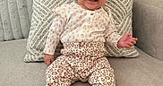 Samantha is registered to the contest to win money with this photo: baby, child, smiling, sitting, portrait, indoor, couch, sofa, pillow, blanket, bow_headband, leopard_print, outfit, shoes, fashion, happy, infant, living_room, cozy, photography