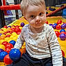 Ayden a rejoint le concours — aidez-le/la à gagner de superbes lots ! amusement, ball, ball_pit, child, colorful_balls, eyes, face, happy, indoor_playground, pants, play_area, playing, portrait, recreation, safety_net, shirt, sitting, socks, toddler, toy