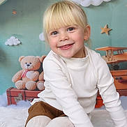 Lyana participe au concours pour gagner de l'argent avec cette photo : child, toddler, smiling, blonde_hair, bangs, white_turtleneck, brown_shorts, white_tights, sitting, portrait, teddy_bear, suitcase, toy_plane, decorative_stars, cloud_backdrop, earring, studio_backdrop, soft_rug, playful, innocent