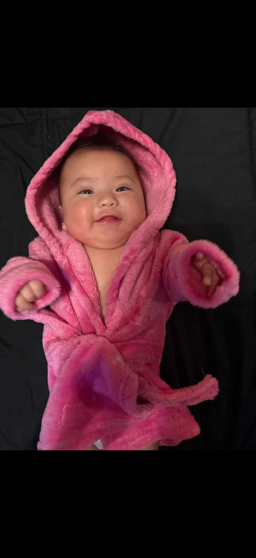Valeria Rose is registered to the contest to win money with this photo: baby, infant, pink_robe, hood, smile, cheeks, cute, portrait, cozy, lying_down, blanket, soft_texture, baby_clothing, cheerful, indoor, skin, hand, eyes, adorable, child