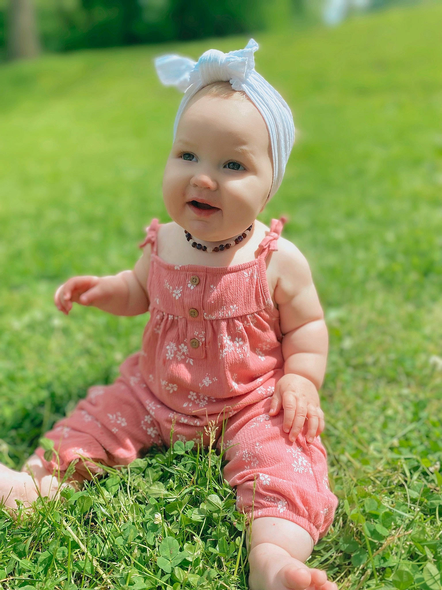 Freyja is registered to the contest to win money with this photo: baby_toddler_clothing, dress, eye, fun, gesture, grass, grassland, green, happy, head, human_body, lawn, meadow, people_in_nature, person, pink, plant, smile, thumb, toddler