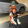 baby, child, stroller, evolur, smiling, happy, indoor, car, vehicle, garage, floor, seat, clothing, person, wheel, footrest, handlebar, safety_harness, modern, cute