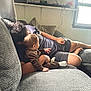 baby, child, adult, couch, sofa, living_room, window, curtains, pillow, casual_clothing, relaxing, indoor, natural_light, person, socks, hair, skin, hand, furniture, home