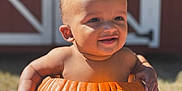 Akari-Reece is registered to the contest to win money with this photo: baby, pumpkin, smiling, outdoor, child, autumn, sunlight, barn, cute, face, hands, skin, seasonal, hollowed_pumpkin, fall, nature, happy, portrait, grass, texture