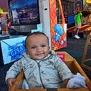 Akari-Reece joined the competition — help win amazing prizes! baby, child, smiling, high_chair, hoodie, arcade, gaming_machine, squidward, wooden_furniture, indoor, person, cute, playful, colorful, clothing, seat, carpet, entertainment, happy, casual