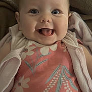 Remi is registered to the contest to win money with this photo: baby, infant, smiling, tongue_out, face, eyes, clothing, floral_pattern, blanket, cozy, cute, happy, portrait, child, indoors, soft_lighting, apparel, person, young, head