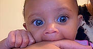Sahara joined the competition — help win amazing prizes! adult, baby, bite, child, closeup, curly_hair, cute, expression, eyes, face, hand, holding, human, indoor, interaction, nibble, person, pink_clothing, playful, skin
