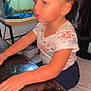 child, girl, floral_shirt, hair_tied, glass_table, fish_tank, aquarium, indoor, seated, focused, earrings, table, hand, face, person, young_child, home, decor, casual_clothing, curly_hair