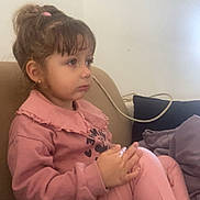Nawell a rejoint le concours — aidez-le/la à gagner de superbes lots ! child, girl, pink_clothing, sitting, couch, indoor, thoughtful, hair_tied, casual_wear, young, person, face, legs_crossed, earrings, long_sleeve, pants, home, relaxed, cozy, calm