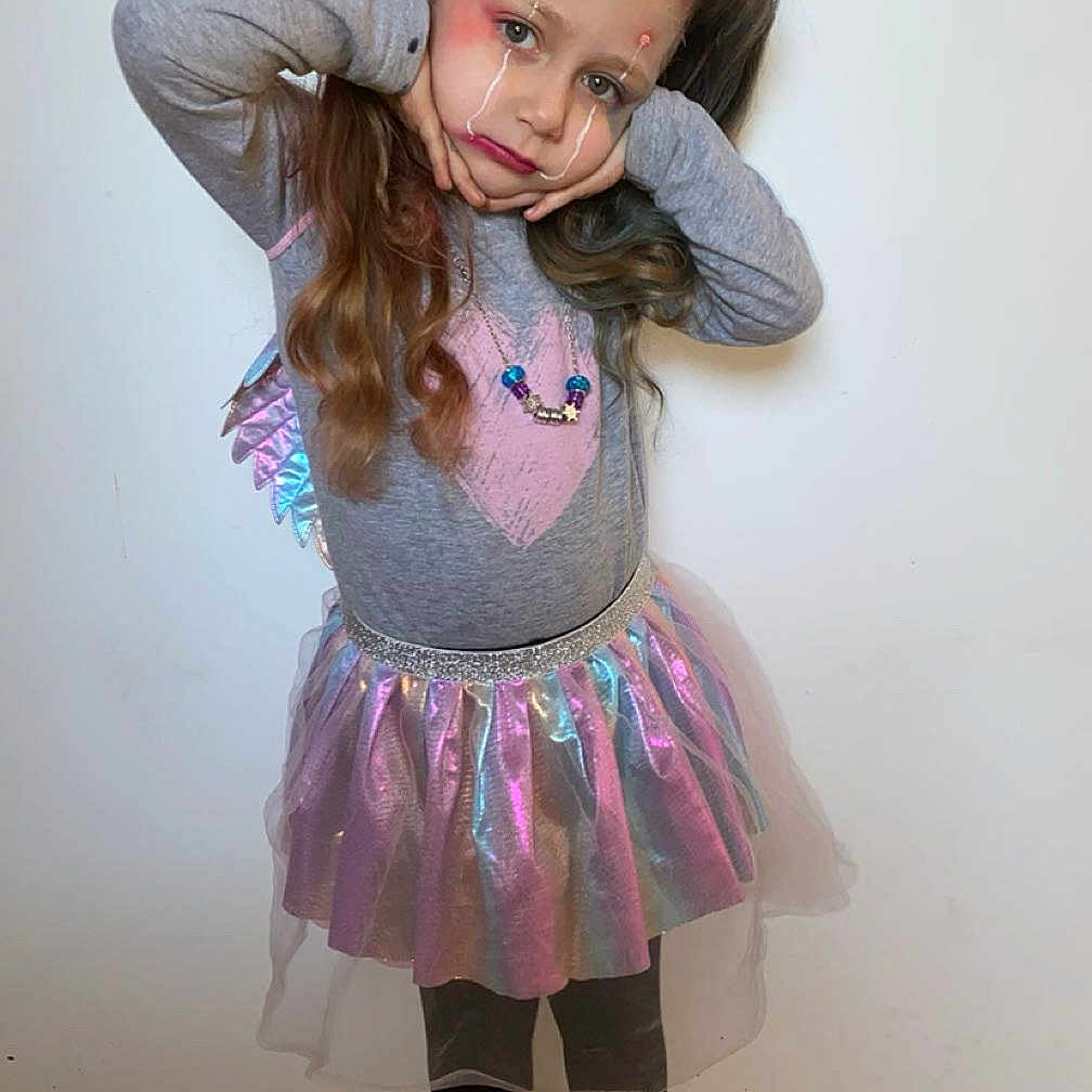 Nawell a rejoint le concours — aidez-le/la à gagner de superbes lots ! boots, casual_clothing, child, colorful, expression, face_paint, floor, girl, gray_top, indoor, long_hair, pigtails, pink_heart, portrait, pose, skirt, socks, sparkly, standing, wall