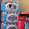 animal, beverage, carpet, cat, coca_cola, container, curiosity, floor, hiding, household, indoor, packaging, peeking, pet, plastic_wrap, playful, soda_boxes, stack, wall, water_bottles