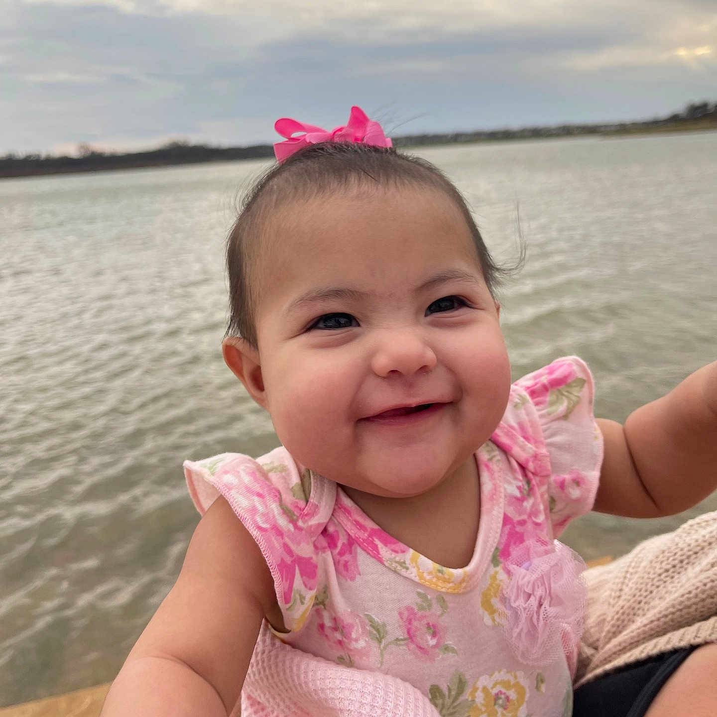 Renesmi is registered to the contest to win money with this photo: baby, clothing, face, happy, head, lake, nature, outdoors, person, photography, pier, port, portrait, sea, sitting, sky, smile, t_shirt, water, waterfront