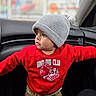 Royal is registered to the contest to win money with this photo: toddler, child, hat, knit_hat, red_sweatshirt, dinosaur, car_interior, portrait, casual_clothing, curious, young_child, indoors, cute, winter_clothing, long_sleeves, pants, standing, looking_away, small_person, baby_face