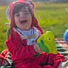 child, toddler, baby, smiling, laughing, red_clothing, hat, bubbles, toy, outdoor, grass, blanket, happy, playful, sunlight, face, sitting, fun, daytime, cute
