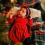 Eliana is registered to the contest to win money with this photo: baby, child, red_dress, headband, bow, plaid_blanket, christmas_tree, holiday, festive, cozy, indoor, infant, cute, portrait, soft_lighting, decor, seasonal, warm, curious, smiling