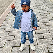 Tristan is registered to the contest to win money with this photo: toddler, child, denim_jacket, blue_beanie, mickey_mouse, white_tshirt, jeans, white_sneakers, paved_street, outdoor, serious_expression, standing, urban, sidewalk, fashion, casual_clothing, person, young_child, cold_weather, street