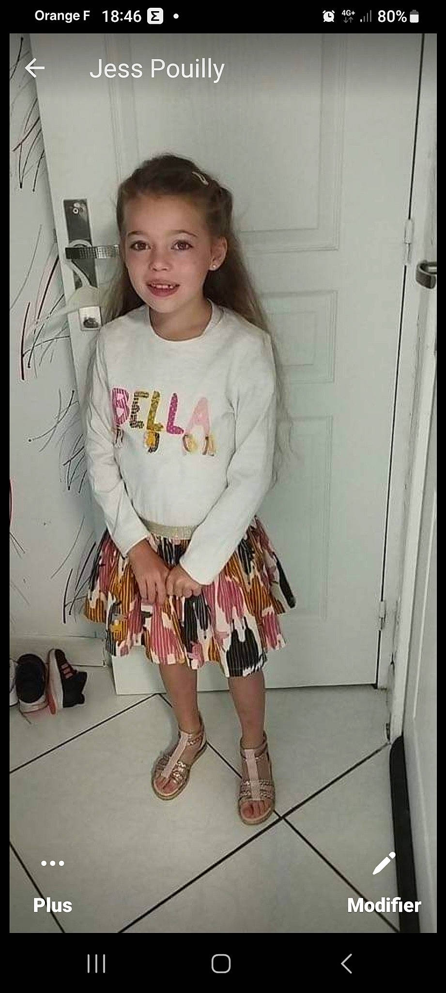 Clara participe au concours pour gagner de l'argent avec cette photo : baby_toddler_clothing, clothing, day_dress, embellishment, fashion_design, foot, happy, human_leg, iris, joy, knee, neck, pattern, person, pink, sandal, sleeve, smile, t_shirt, thigh