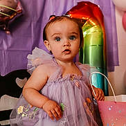 Miracle joined the competition — help win amazing prizes! toddler, child, birthday, dress, purple, balloons, gift_bag, party, curious, sitting, face, eyes, hair, celebration, indoor, decorations, cute, person, smile, young