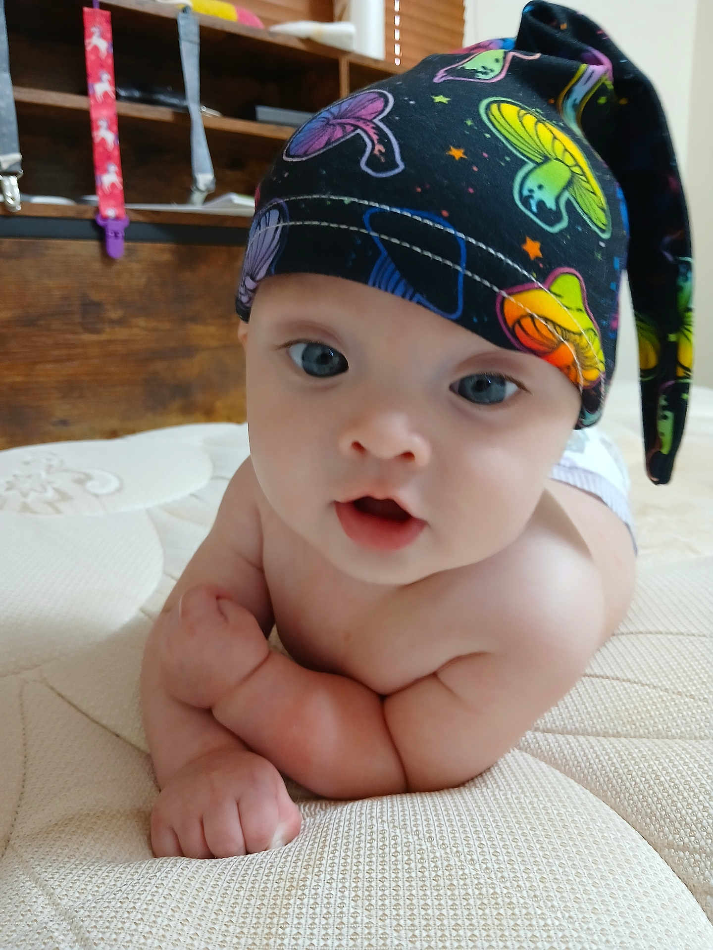 Miracle joined the competition — help win amazing prizes! baby, infant, hat, mushroom_pattern, blue_eyes, bare_chest, curious_expression, indoor, mattress, wooden_furniture, child, cute, portrait, skin, person, headwear, colorful, closeup, young, resting