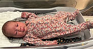 Tiana is registered to the contest to win money with this photo: newborn, baby, infant, child, portrait, floral_clothing, sleeper, hospital, bassinet, blanket, bedding, lying_down, awake, face, eyes, head, indoors, medical_setting, cozy, photography