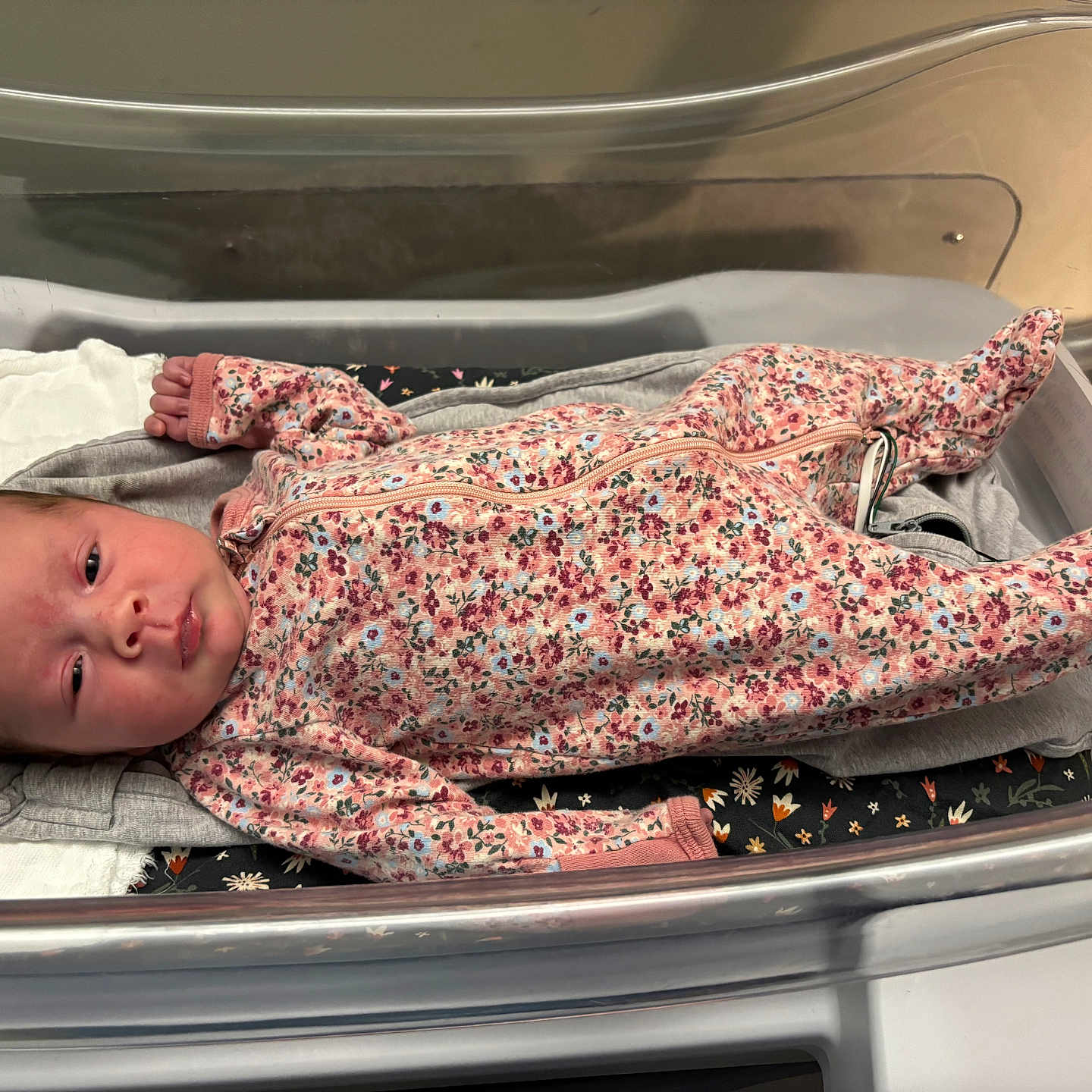 Tiana is registered to the contest to win money with this photo: newborn, baby, infant, child, portrait, floral_clothing, sleeper, hospital, bassinet, blanket, bedding, lying_down, awake, face, eyes, head, indoors, medical_setting, cozy, photography