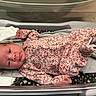 Tiana joined the competition — help win amazing prizes! newborn, baby, infant, child, portrait, face, eyes_open, lying_down, floral_outfit, romper, pink_clothing, blanket, changing_table, bassinet, baby_bedding, indoor, close_up, alert, cozy, photography