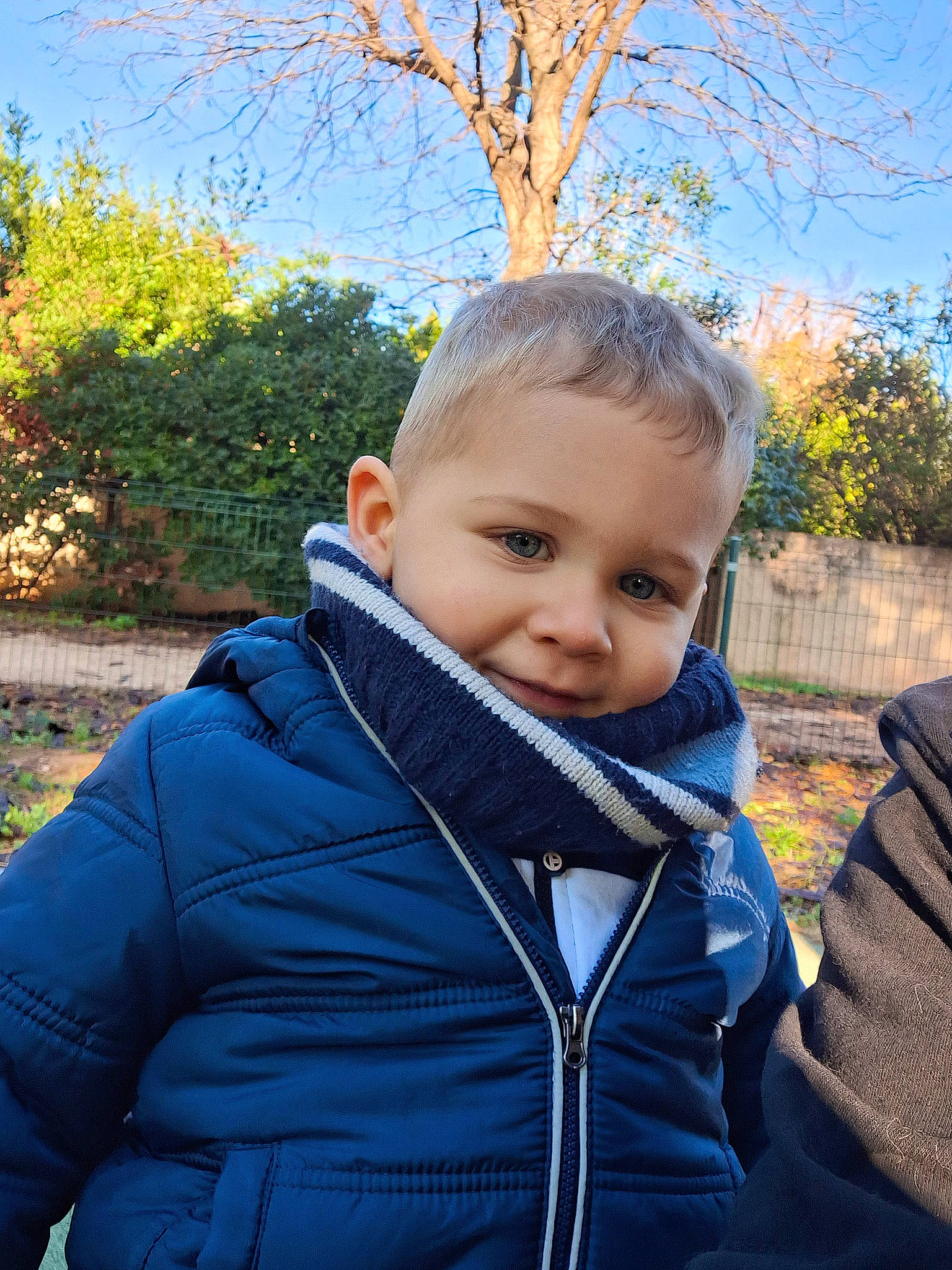 Nathan a rejoint le concours — aidez-le/la à gagner de superbes lots ! baby, blond, electric_blue, fun, fur, grass, happy, hood, jacket, leisure, outerwear, people_in_nature, person, plant, sitting, sky, sleeve, toddler, tree, winter