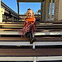 child, smiling, girl, orange_clothing, dress, boots, steps, porch, outdoor, daylight, sunny, blue_sky, wood, rustic, autumn, leaves, smile, person, fashion, happy